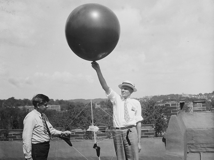 Two men launching a weather balloon from the roof of the Weather Bureau building in Washington, D.C., circa 1936 or 1937.